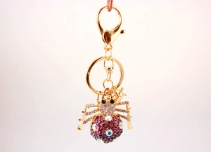 Close-up of colorful rhinestone spider keychain with gold base and purple crystals