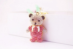 Detailed close-up of a teddy bear keychain with pink rhinestones and gold plating