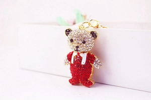 Close-up of a sparkling rhinestone cartoon bear keychain with vibrant red and white crystals