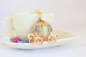 Detailed view of pumpkin carriage keychain with green cat eye stone and crystal inlay