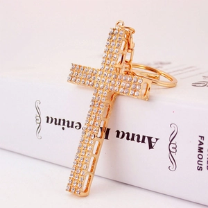 Portachiavi a croce in metallo dorato con strass bianchi scintillanti su libri decorativi