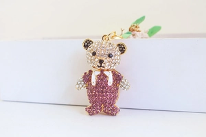 Detailed view of gold bear keychain with purple and white crystals on display