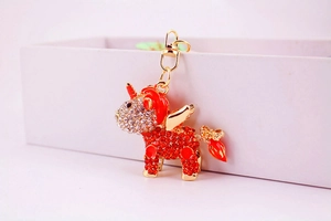 Macro view of gold unicorn keychain with red rhinestones and orange enamel details