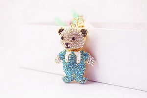 Detail of cute bear keychain with blue and white rhinestones on gold plating