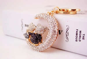 Detailed view of moon-shaped rhinestone keychain with two cuddling bears and gold clasp