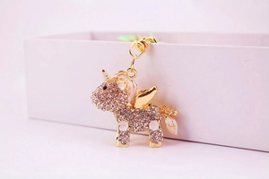 Detail of a sparkling golden unicorn keychain with pink rhinestones and enamel wings
