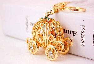 Detailed view of a golden pumpkin carriage keychain with white rhinestones and green enamel