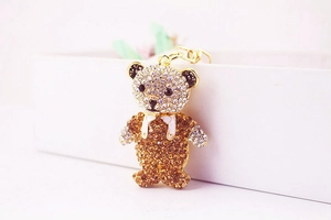 Detailed side view of a sparkling rhinestone bear pendant with golden metal clasp hook