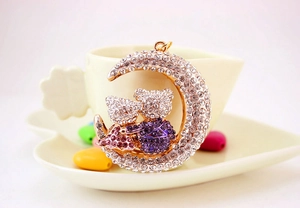 Close-up of sparkling rhinestone moon keychain with cute bears on a gold finish base