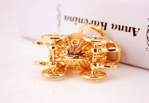 Detailed close-up of a golden pumpkin carriage keychain with rhinestones on a book