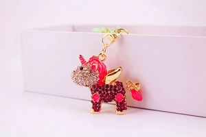 Detail of pink crystal unicorn keychain with gold wings on a white gift box