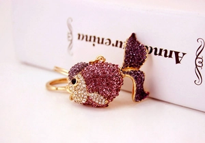Macro detail of a crystal-encrusted goldfish keychain with purple and white rhinestones