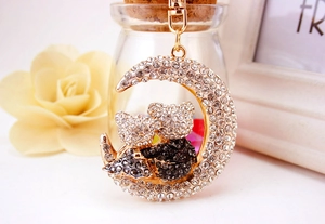 Detailed macro of crystal crescent moon keychain with two bears on white background