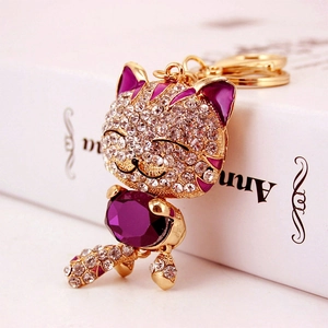 Porte-clés chat porte-bonheur doré avec cristal violet et strass sur livre blanc