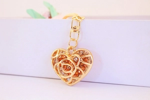 Close-up of golden heart keychain with hollow rose pattern and sparkling rhinestones