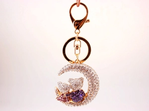 Close-up of golden moon bear keychain with purple and pink rhinestones and white crystals