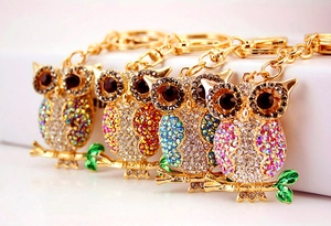 Detail view of colorful rhinestone owl keychains with gold plating and enamel leaves