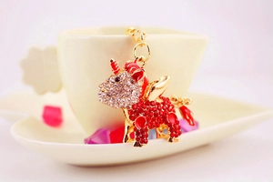 Close-up of golden unicorn keychain with red rhinestones and enamel wings on a cup
