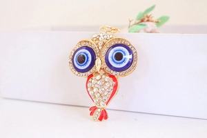 Détail du porte-clés hibou en cristal étincelant avec charmes d'yeux bleus et dorures