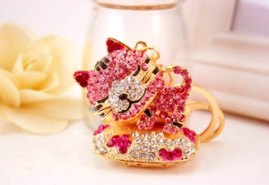 Dettaglio portachiavi a gatto in cristallo rosa e bianco con cuore metallico