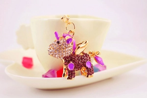 Close-up of a golden unicorn keychain with purple crystals hanging on a ceramic cup