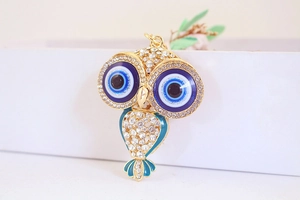 Détail du porte-clés hibou avec strass blancs, yeux bleus de protection et plumes émaillées