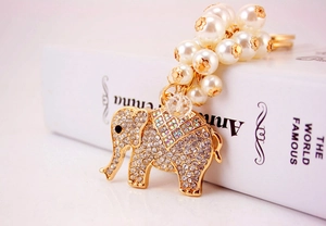 Detail of gold elephant keychain with sparkling rhinestones and white pearl strap charm