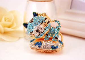 Dettaglio ravvicinato di un portachiavi a forma di gatto dorato con strass blu