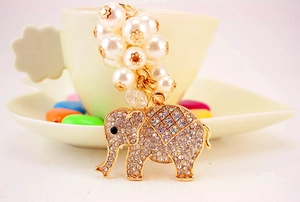 Close-up of golden elephant keychain with sparkling rhinestones and white pearl beads