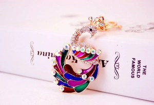 Detail of colorful enamel peacock keychain with sparkling crystals on book
