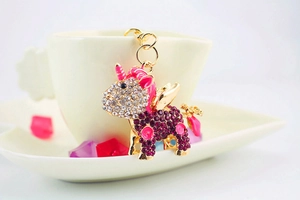 Detail of creative rhinestone unicorn keychain with gold wings and enamel on white tray