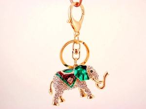 Gros plan du porte-clés éléphant doré orné de strass brillants et détails en émail vert
