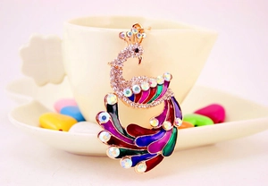 Close-up of colorful peacock keychain with vibrant enamel wings and sparkling rhinestones