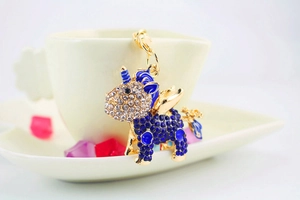 Close-up of gold-tone unicorn keychain with blue and clear rhinestones on a white cup