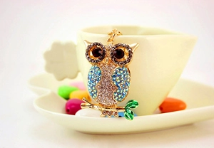 Detail of colorful crystal owl keychain with blue rhinestones on a gold branch base