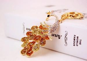 Macro shot of gold peacock keychain with crystal rhinestones on a white book