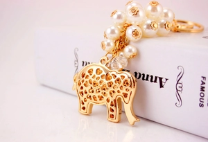 Detail of golden hollow elephant keychain with white faux pearls and faceted beads