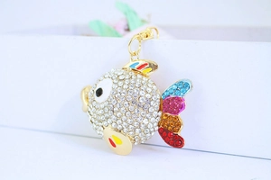 Macro detail of a golden fish keychain featuring white rhinestones and colorful fins