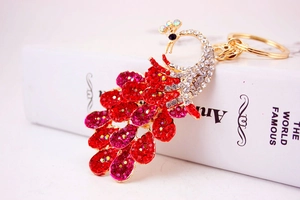 Detail of colorful peacock keychain with vibrant red and pink rhinestones on gold alloy