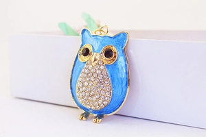 Détail du porte-clés hibou en émail bleu avec strass et finition en métal doré élégant