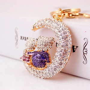 Sparkling moon and bear keychain with rhinestones and purple accents on white background