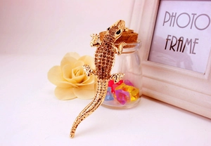 Macro detail of lizard keychain with brown rhinestones and gold plating on a floral setup