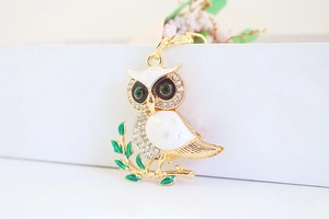 Close-up of owl keychain with white enamel, crystal rhinestones, and emerald gem eyes