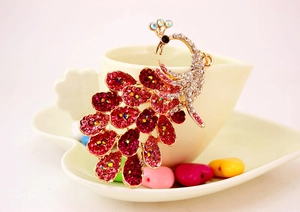 Detailed close-up of a peacock pendant featuring vibrant red and pink rhinestones