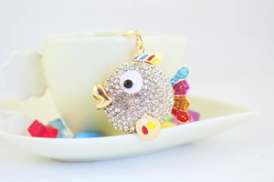 Macro shot of tropical fish keychain with colorful enamel and crystal detailing on white cup