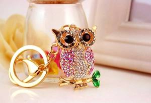 Close-up of pink and white rhinestone owl keychain with gold metal and green leaves