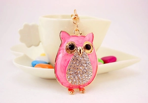 Détail du porte-clés hibou en émail rose marbré avec bordure dorée et strass brillants