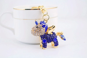 Detail of royal blue rhinestone unicorn keychain with gold wings on ceramic cup