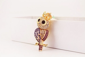 Détail macro du porte-clés hibou avec strass violets étincelants et couronne dorée