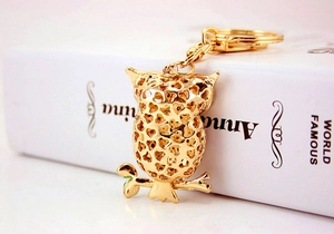 Detailed close-up of a golden owl keychain with heart-shaped hollow patterns on metal surface